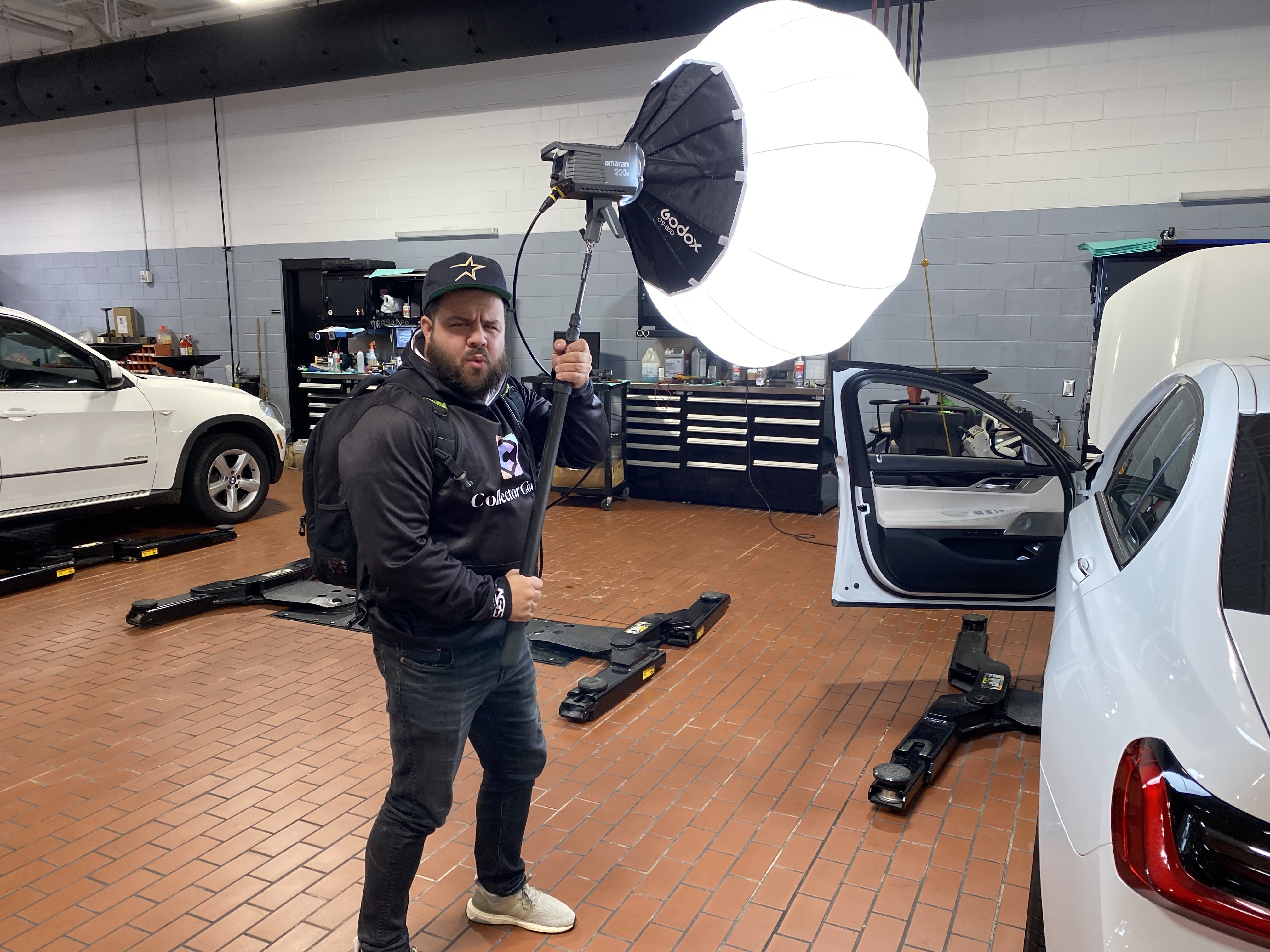 Crew member holding a lighting modifier beside a BMW during production.